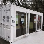 Container espositivo bianco con vetrate – Struttura modulare per eventi e fiere con ampie vetrate, adibita a showroom o stand promozionale.