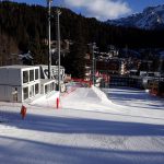 Container per eventi su pista da sci – Struttura modulare in container bianchi a due livelli, posizionata su una pista da sci con vista sulle montagne.