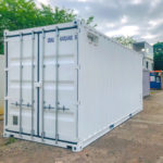 Container shelter elettrico bianco con doppia porta rinforzata e prese di ventilazione, progettato per proteggere quadri elettrici, inverter e sistemi di accumulo energetico.