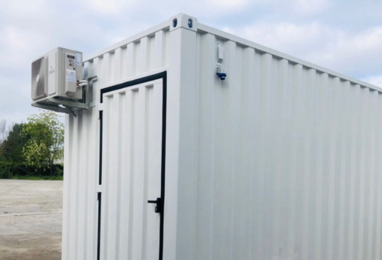 Shelter cabina elettrica bianco con porta rinforzata e sistema di climatizzazione, ideale per la protezione di quadri elettrici, inverter e trasformatori.
