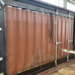 Container in fase di lavorazione - Modifica strutturale di un container marittimo con rinforzi e aperture personalizzate.