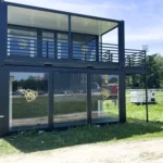 Struttura modulare a due piani brandizzata Radio 105, con pareti vetrate al piano terra e terrazza panoramica superiore, installata per eventi musicali live.