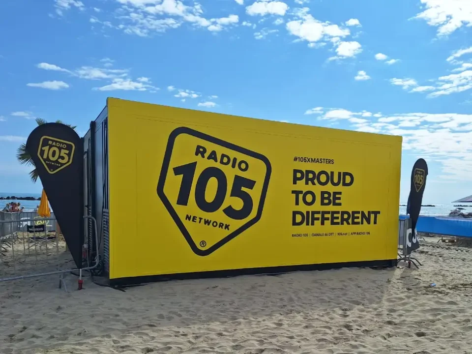 Container modulare giallo brandizzato Radio 105 installato sulla spiaggia di Senigallia per l’evento XMasters, utilizzato come studio radiofonico temporaneo a pochi metri dal mare.