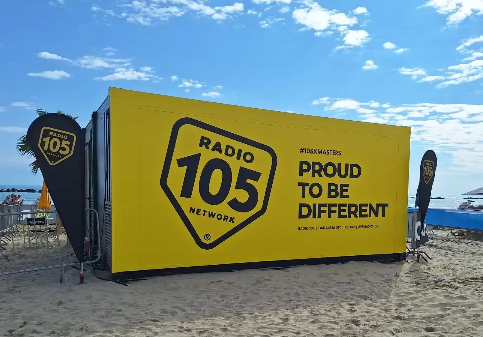 Container modulare giallo brandizzato Radio 105 installato sulla spiaggia di Senigallia per l’evento XMasters, utilizzato come studio radiofonico temporaneo a pochi metri dal mare.