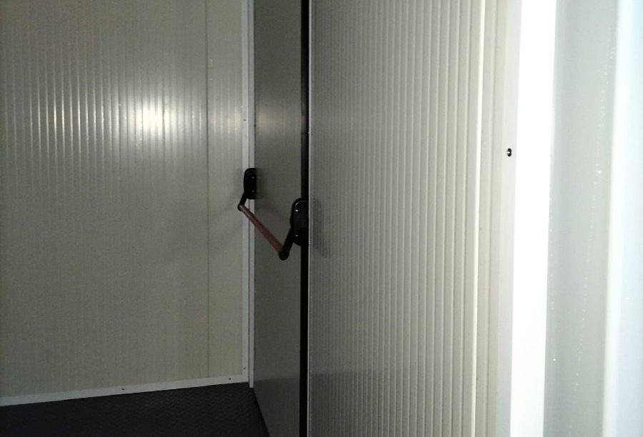 Porta interna di un container coibentato con barra antipanico, progettato per garantire sicurezza e isolamento termico in ambienti controllati.