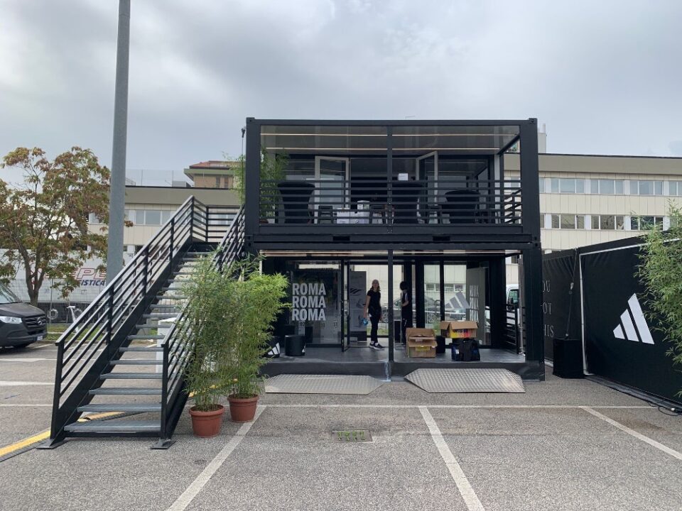 Container espositivo Adidas a due piani per la Mezza Maratona di Roma 2024, con struttura modulare nera, scale laterali e aree di accoglienza brandizzate.