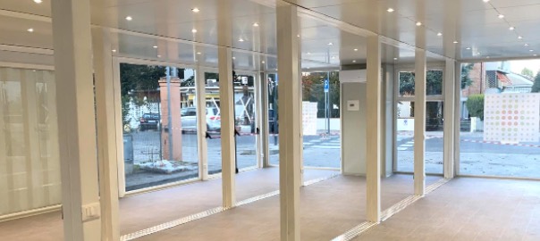 Interno di una struttura modulare prefabbricata con ampie vetrate, illuminazione a LED e pavimento in gres, utilizzata come sala d'attesa ospedaliera.