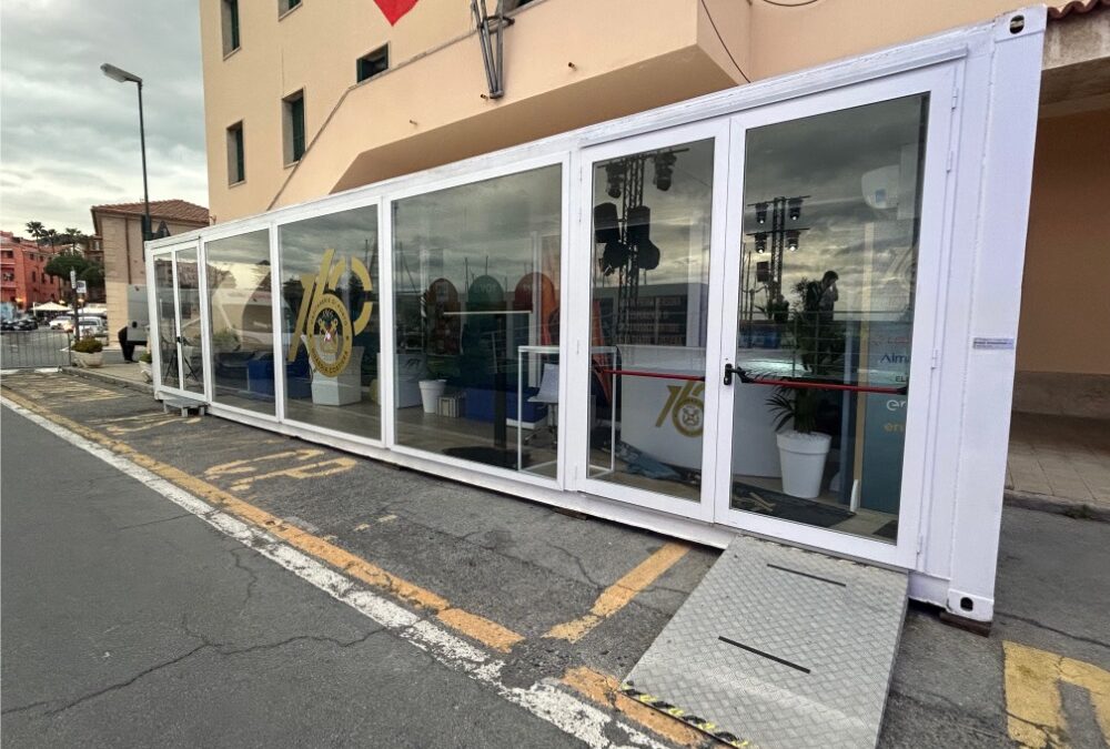 Vista laterale del showbox container per la Guardia Costiera, con ingresso principale, loghi ufficiali e installazione in una location strategica a Sanremo.