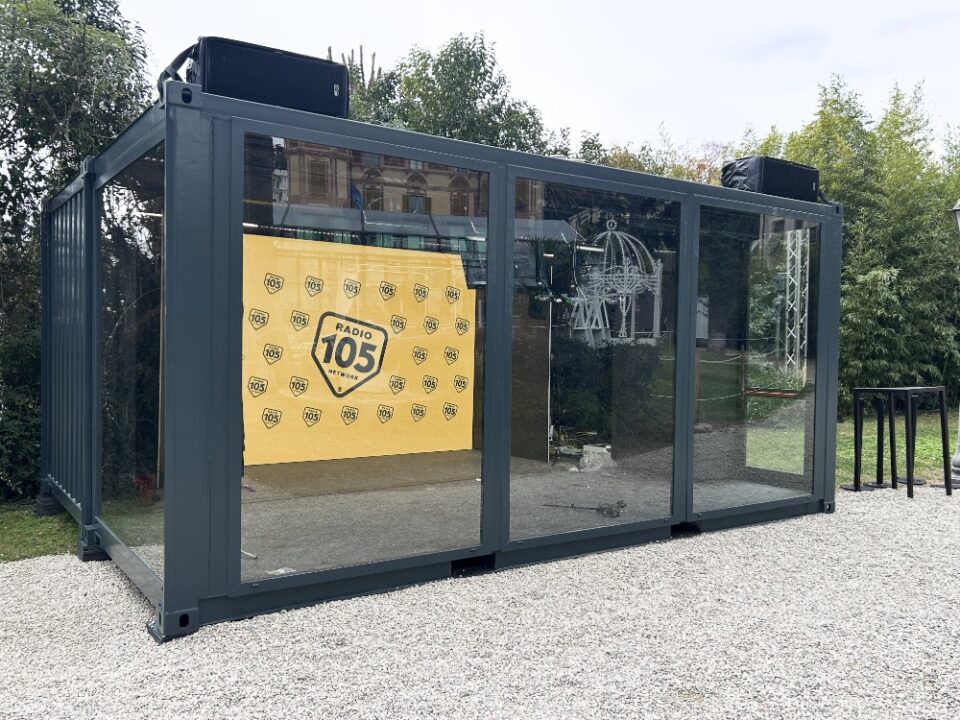 Studio Radio 105 per Sanremo 2025 in un container vetrato, con arredamento moderno e area dedicata a interviste e dirette radio.