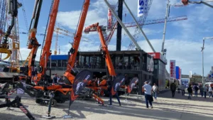 Stand modulare Jekko a Bauma 2025 con gru compatte in esposizione e container su due piani, collocato tra altre strutture del quartiere fieristico.