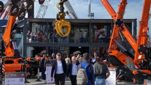 Stand Jekko a Bauma 2025 con struttura modulare a due piani e gru in esposizione, circondato da visitatori e attrezzature da cantiere.