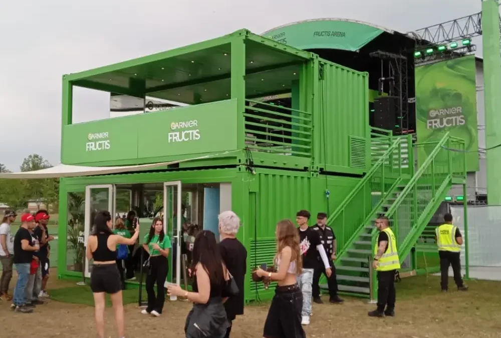 Struttura modulare containerizzata brandizzata Garnier Fructis al Nameless Festival 2025, con terrazze VIP, scala esterna e area esperienziale interattiva.