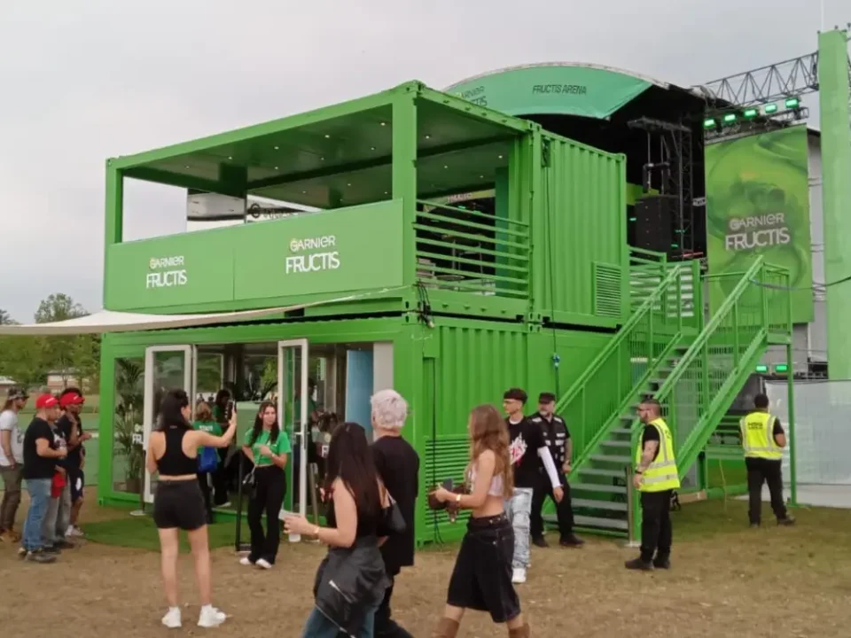 Struttura modulare containerizzata brandizzata Garnier Fructis al Nameless Festival 2025, con terrazze VIP, scala esterna e area esperienziale interattiva.