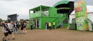 Container brandizzati Garnier Fructis accanto al palco principale del Nameless Festival 2025, con scala esterna e flusso di pubblico.