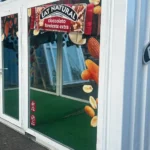 Container showbox Eat Natural personalizzato con vetrate, branding esterno e pavimentazione in erba sintetica.