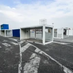 Container bianchi e blu posizionati nell’area esterna di EICMA 2025 durante l’allestimento dell’area Your Urban Mobility, con moduli showbox vetrati pronti per essere installati.
