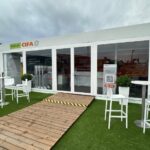 Struttura modulare vetrata CIFA a SaMoTer con ingresso centrale, pedana in legno e area hospitality esterna.