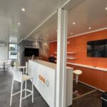 Vista interna della struttura modulare CIFA con reception, area merchandising, tavoli e superfici vetrate.