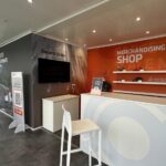 Bancone reception e merchandising CIFA con pareti grafiche, monitor ed esposizione di prodotti brandizzati.