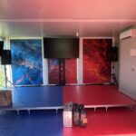 Interno climatizzato della struttura Vigorsol con palco, schermi, diffusori audio e allestimento grafico coordinato.