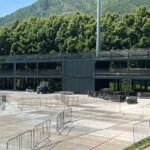 Vista frontale della VIP Lounge in fase di allestimento con container sovrapposti, terrazze e barriere di sicurezza.